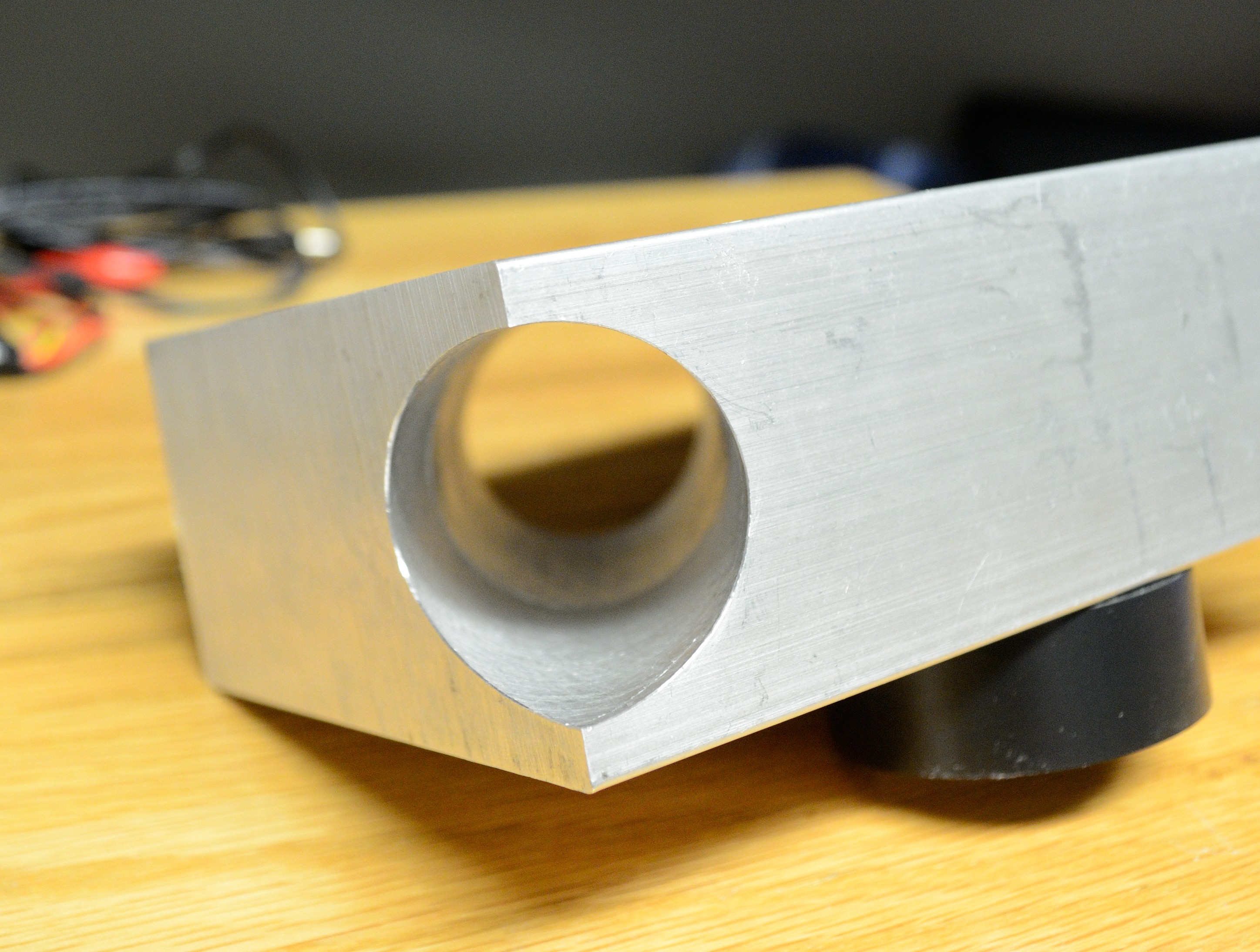 A deep bore is cut at an angle through a solid aluminum block